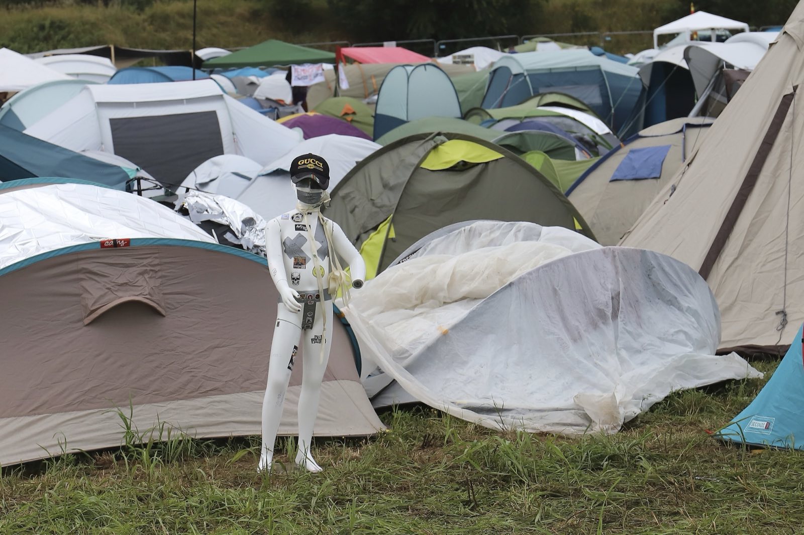 Setki namiotów na polu namiotowym festiwalu Pol'and'Rock, między nimi biały manekin w czapce